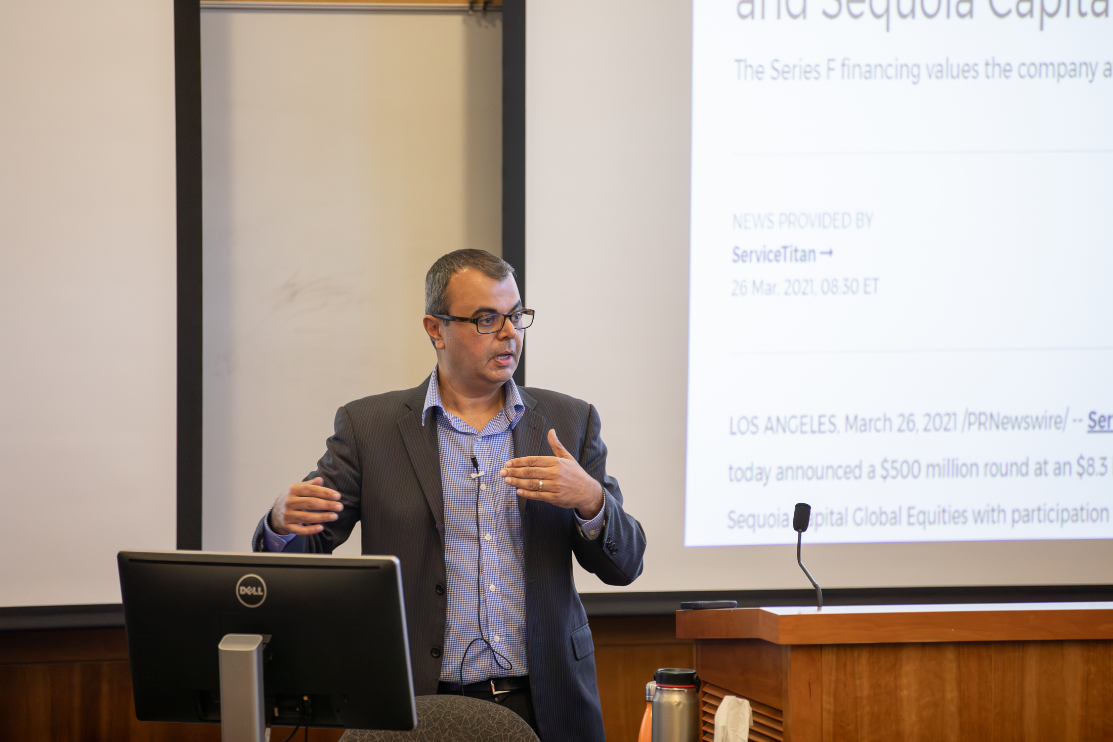 A man standing at a podium and speaking to a class.