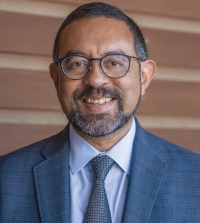 UC Davis Law Professor Ash Bhagwat wearing a suit and smiling at the camera.